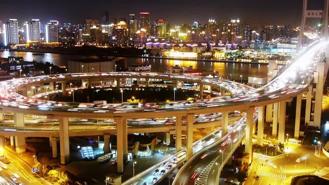 Aerial freeway busy city rush hour heavy traffic jam highway Shanghai at night,timelapse,nanpu overpass interchange,Brightly lit urban skyline,busy shipping sailing on huangpu river.