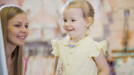 A girl admires herself in the mirror in the children's clothing store