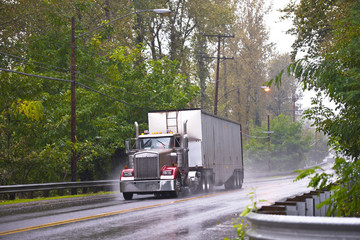 Classic Big rig truck in raining weather wet road