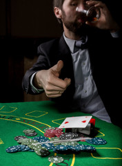 Poker player showing a losing combination in a poker cards, man drinks whiskey from grief