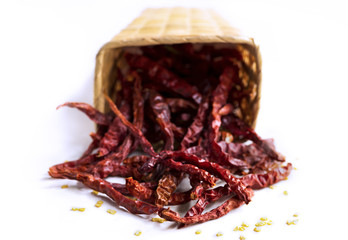 Closeup of red dry chili peppers in basket on white background.