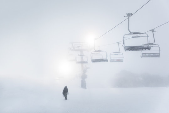 Man walking through snow with chairlift