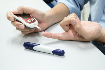 Medicine, diabetes, glycemia, health care and people concept - close up of man hands checking blood sugar level by glucometer
