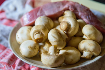 Fresh white mushrooms and raw meat on plate