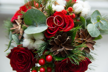 Fototapeta na wymiar winter wedding bouquet of red roses with wedding rings.