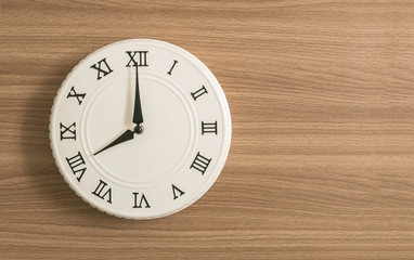 Closeup white clock for decorate in 8 o'clock on wood desk textured background with copy space
