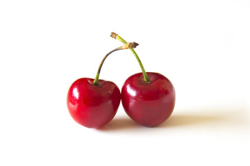 Two cherries against a white background