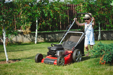 Fototapeta na wymiar little boy mows lawn with mower