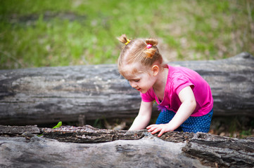 Beautiful little girl on a walk in the park in spring, summer. The girl walks through the woods, resting, having fun. A child in a pink blouse and jeans. Girl with funny tails. The girl knows the worl