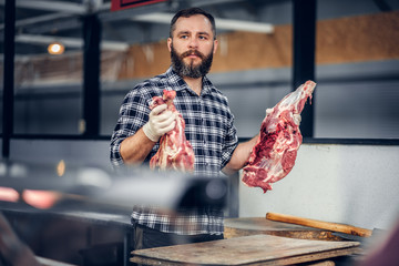 Portrait of a bearded meat man holds fresh cut meat.