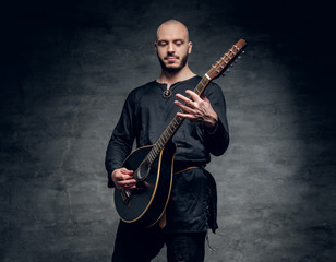 Studio portrait of a man in traditional Celtic clothes playing on mandolin.