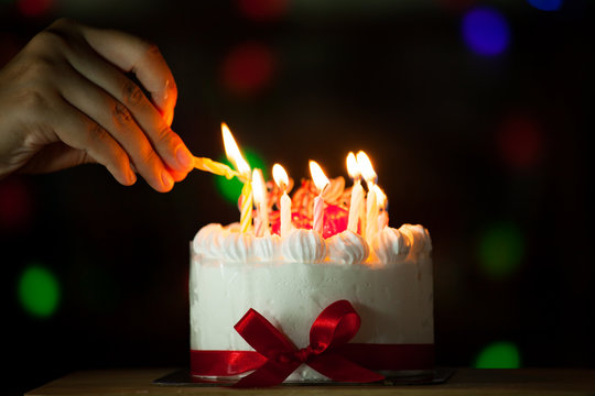 Woman Hand Lighting Candle On Birthday Cake In Dark Tone