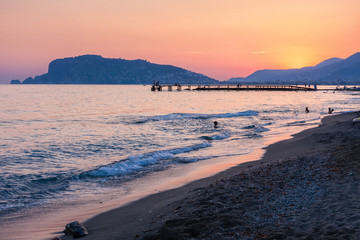 Fototapeta na wymiar Beach of Alanya at the sunset, Turkey. At the background Alanya Peninsula