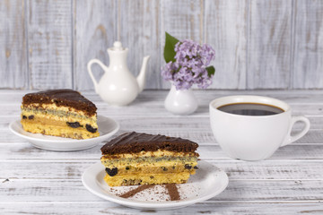 Chocolate piece of cake from biscuit dough with poppy seed, prune and walnuts and cup of coffee