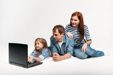 Happy family Father, mother and child lying on the floor with laptop on white background isolated