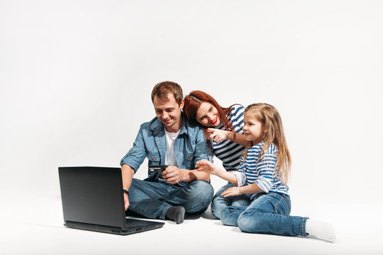 Happy family Father, mother and child lying on the floor with laptop and credit card on white background isolated