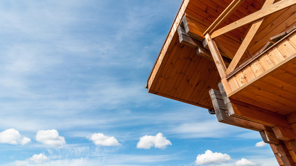 Part of the facade and roof of an ecologically clean wooden house on a background of a cloudy blue sky