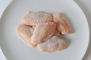 Fresh raw chicken wings on white dish with white background