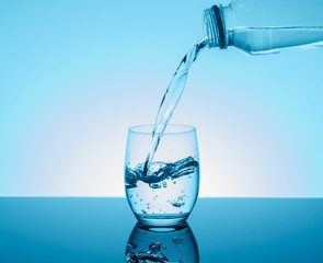 Bottle with creative splashing water in the glass