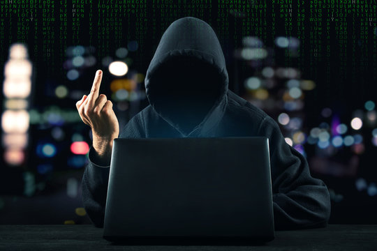 Hacker in front of his computer show middle finger. Dark face