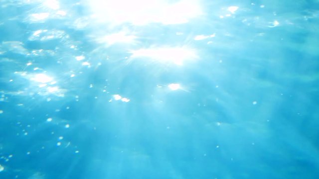 Beautiful underwater sea scene view with natural light rays, shining through the water's glittering and moving surface. 3840x2160