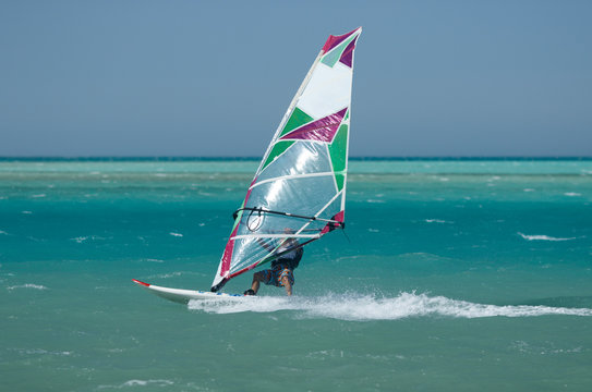 Recreational water sports: windsurfing. Windsurfer surfing waves and jumping high in the sea on a windy day. Extreme sports action with wind and water. Recreational sporting activity
