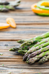 Raw green asparagus and veggies on wooden table. Selective focus