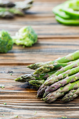 Raw green asparagus and veggies on wooden table. Selective focus