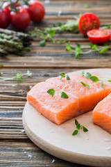 Raw uncooked salmon and vegetables on wooden table