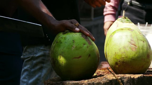 Cutting coconut to extract juice at the market.