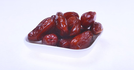 Delicious dried organic dates on bowl isolated over white background.