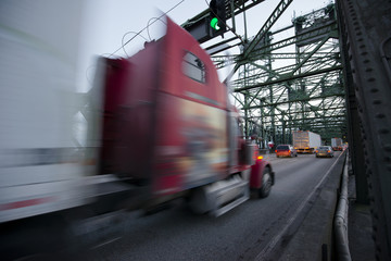 Blurred red semi-truck with trailer on highway over bridge