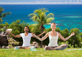 happy couple doing yoga and meditating outdoors