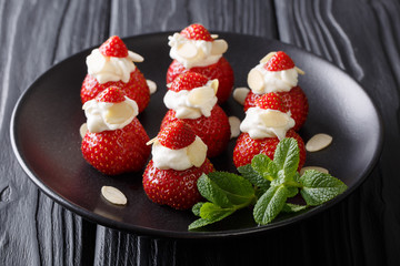 beautiful strawberry dessert with almonds and whipped cream on a plate close-up on a table. horizontal