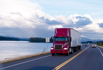 Red semi truck and two trailers on evening road © vit