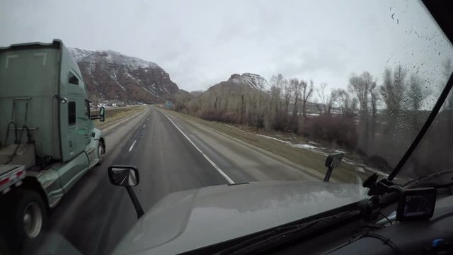 A Flatbed Semi Truck Passes the viewer on a rural highway in Utah, USA.