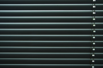 Closed venetian blinds or shutters background. Daylight coming through closed metallic...