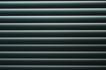 Closed venetian blinds or shutters background. Daylight coming through closed metallic blinds.Nighttime privacy.