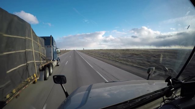 A Flatbed Semi Truck Passes the viewer on a rural highway in Idaho, USA.