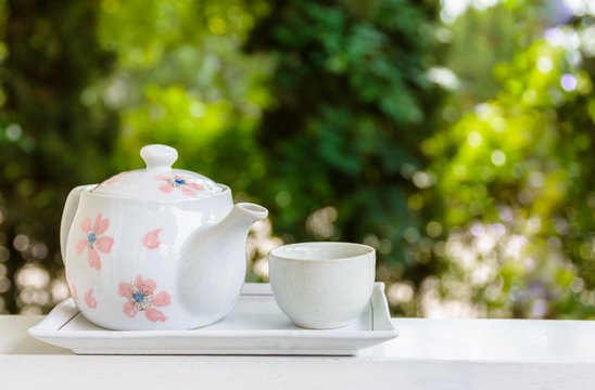 Tea pot with tea cup on balcony.