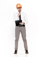 Young construction engineer in orange helmet with folder thinking on white background
