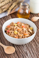 Granola with dried fruits and nuts in white bowl.