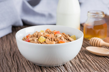 Granola with dried fruits and nuts in white bowl.