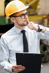 Engineer builder in a helmet holds folder at construction site