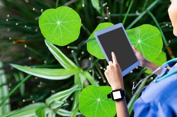 Woman using her tablet against leaves