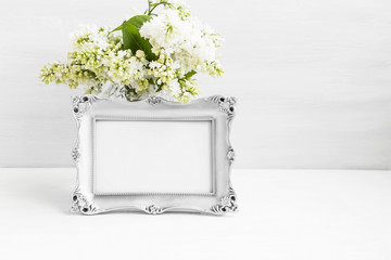 Vintage silver photo frame with lilac flowers on white still life board