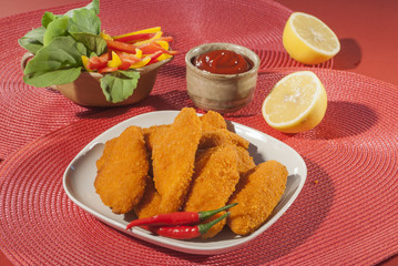Spicy Breaded chicken fillets with red chilly lemon and cherry tomatoes with ketchup and bell pepper salads