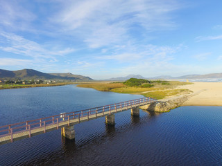 Bridge over the Lagoon by the Ocean with Blue Skies and Clouds