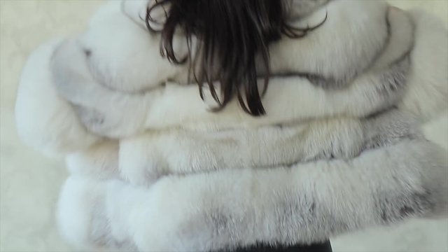 Young sexy girl shows fashionable arctic fox fur short coat in studio