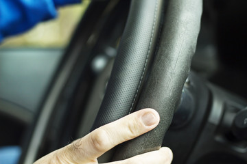 Pracownik serwisu przymierza nakładkę na kierownicę samochodu. Auto detailing wnętrza samochodu. Nakładka na kierownicę. Odnawianie wnętrza samochodu, nakładka na kierownicę. © Tomasz